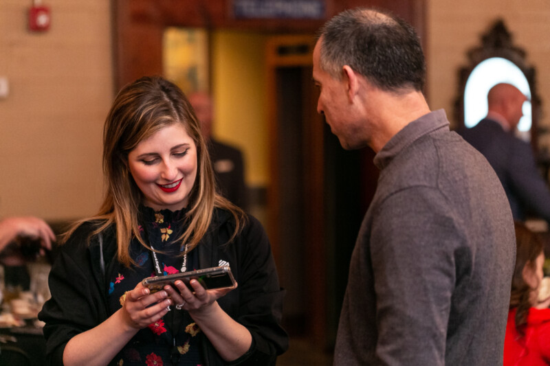 Photo of a Markforged employee showing her phone to a partner at an event